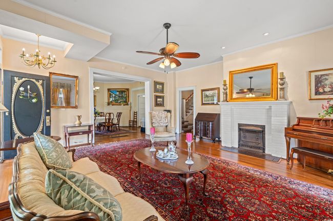 Living area with a ceiling fan, stairway, a chandelier, wood finished floors, and ornamental molding | Image 6