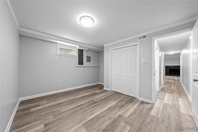 Unfurnished bedroom with visible vents, baseboards, a closet, light wood finished floors, and a tiled fireplace | Image 32