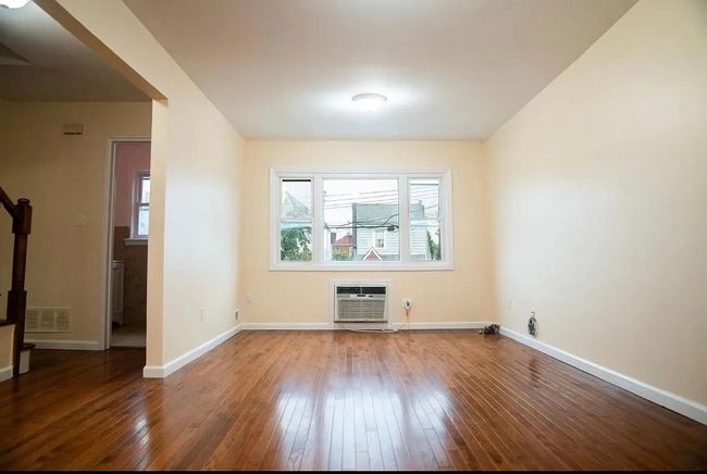 Empty room featuring baseboards, visible vents, a wall unit AC, and hardwood / wood-style flooring | Image 4