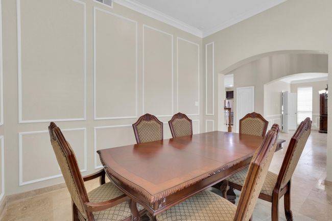 Dining space with arched walkways, a decorative wall, ornamental molding, and visible vents | Image 9