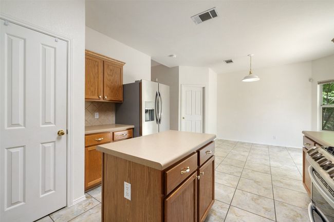 Kitchen with brown cabinetry, backsplash, decorative light fixtures, visible vents, and appliances with stainless steel finishes | Image 13