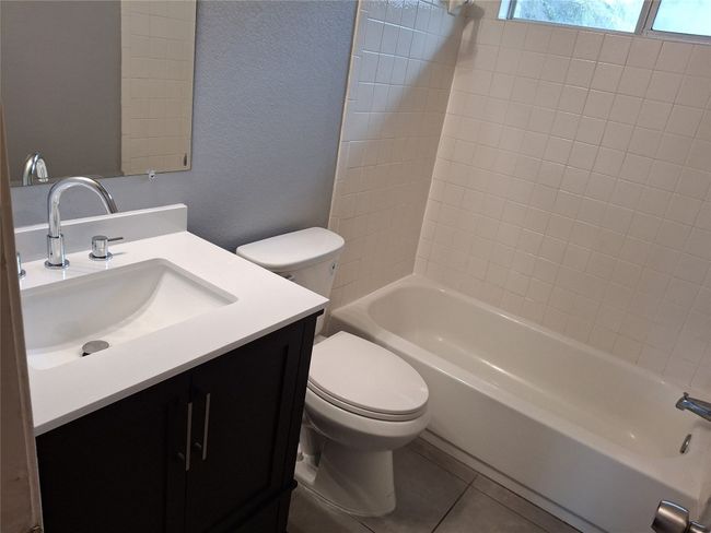 Full bath with a textured wall, new toilet, new vanity, shower combination, and tile patterned flooring | Image 15