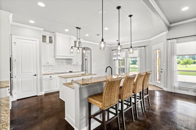 Kitchen featuring a center island with sink, arched walkways, healthy amount of natural light, tasteful backsplash, and recessed lighting | Image 12