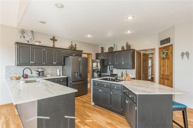 Kitchen featuring a breakfast bar, a sink, stainless steel fridge with ice dispenser, a peninsula, and decorative backsplash | Image 26