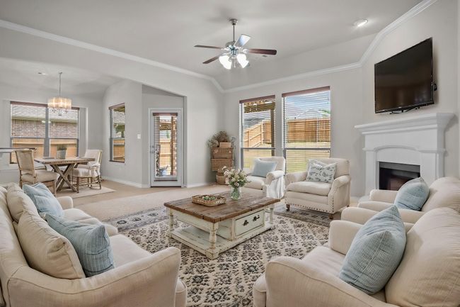 VIRTUALLY STAGED Carpeted living area with crown molding, baseboards, ceiling fan with notable chandelier, and a fireplace | Image 12