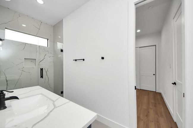 Secondary bathroom features a walk-in shower with tile surround and spacious vanity. | Image 26