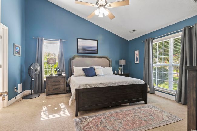 Carpeted bedroom featuring multiple windows, a ceiling fan, and high vaulted ceiling | Image 18