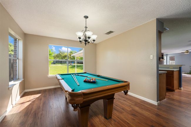 Recreation room featuring a notable chandelier, baseboards, dark wood finished floors, visible vents, and a healthy amount of sunlight | Image 8