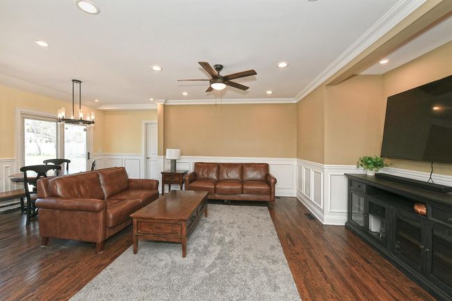 Living room featuring dark wood finished floors, wainscoting, recessed lighting, ceiling fan with notable chandelier, and a decorative wall | Image 25