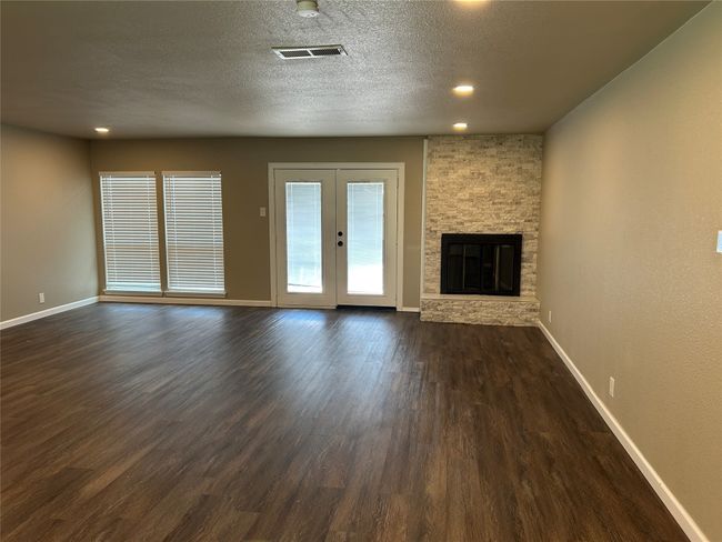 Unfurnished living room with baseboards, dark wood-style flooring, a stone fireplace, recessed lighting, and a textured ceiling | Image 18