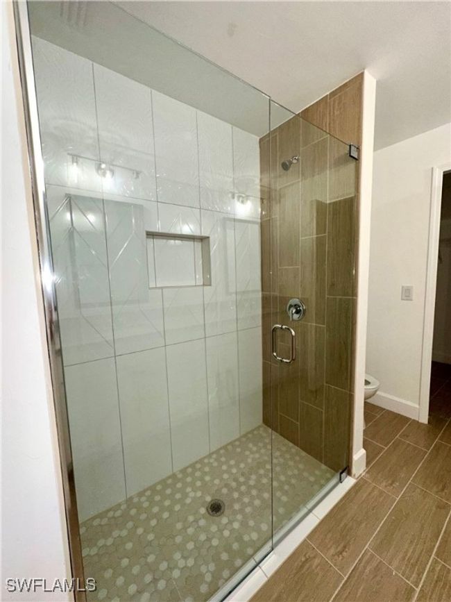 Bathroom featuring toilet and a shower with door | Image 12