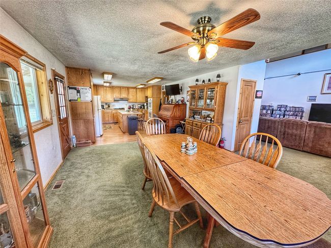 Dining space featuring visible vents, a ceiling fan, light colored carpet, and a textured ceiling | Image 18