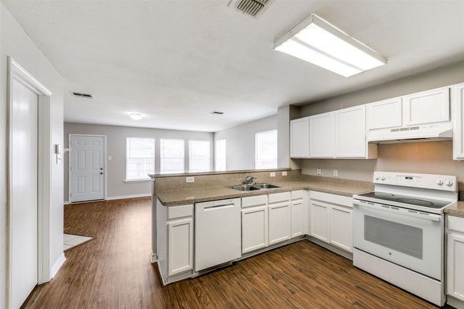 Kitchen featuring white cabinetry, sink, white appliances, and kitchen peninsula | Image 13
