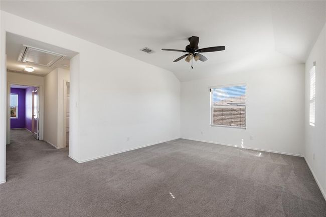 Carpeted spare room with attic access, plenty of natural light, ceiling fan, baseboards, and vaulted ceiling | Image 25