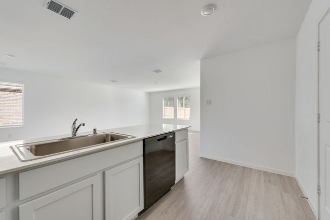 Kitchen featuring dishwasher, light wood-type flooring, light countertops, and white cabinets | Image 12