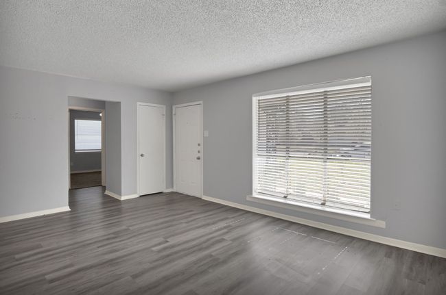 Unfurnished living room featuring a textured ceiling, dark wood-type flooring, and baseboards | Image 4