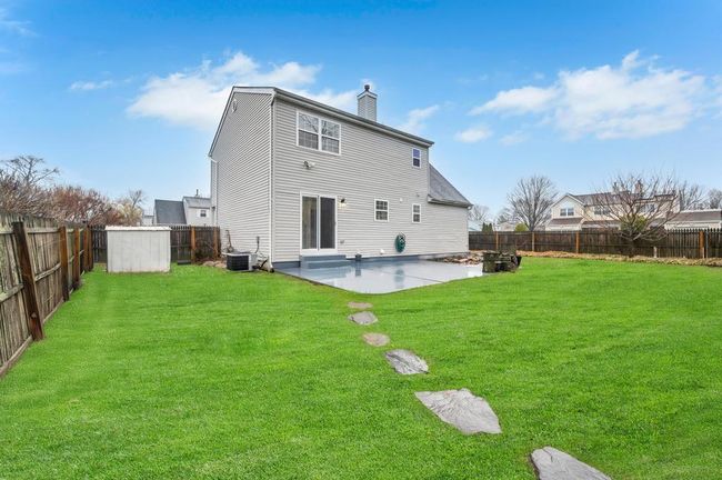 Back of property featuring cooling unit, a patio, a fenced backyard, a yard, and a chimney | Image 22