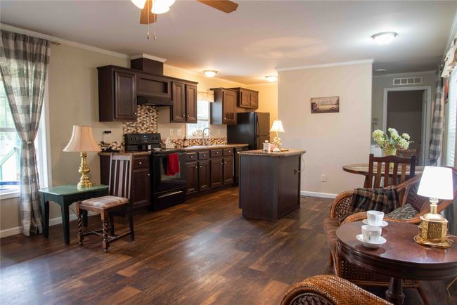 Open concept Kitchen featuring a center island, under cabinet range hood, dark wood finished floors, and black appliances | Image 20
