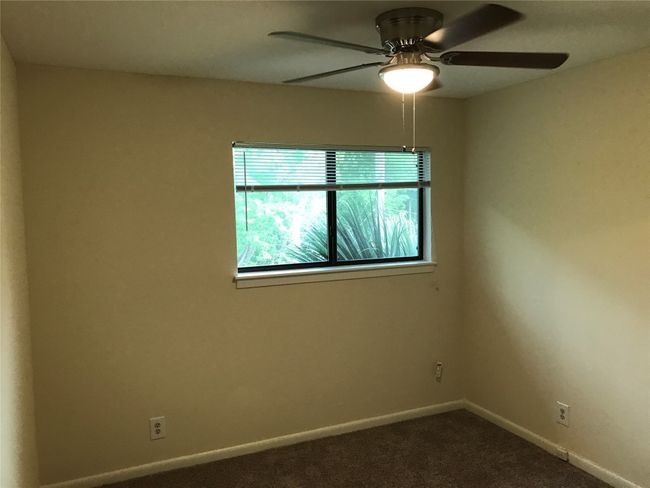 Empty room with baseboards, dark carpet, and a ceiling fan | Image 8
