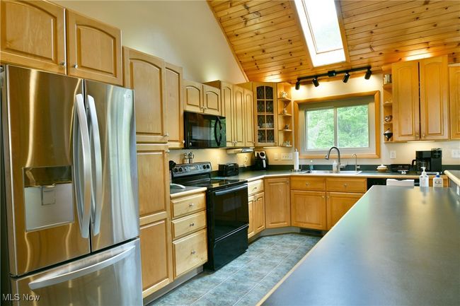 Kitchen with black appliances, open shelves, a sink, wooden ceiling, and rail lighting | Image 13