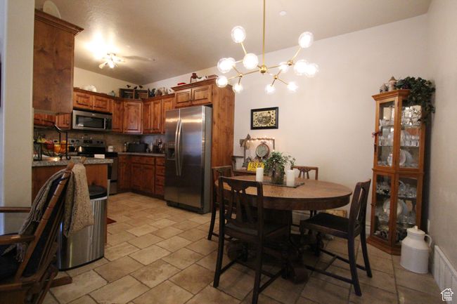 Kitchen with stainless steel appliances, visible vents, backsplash, brown cabinets, and decorative light fixtures | Image 7