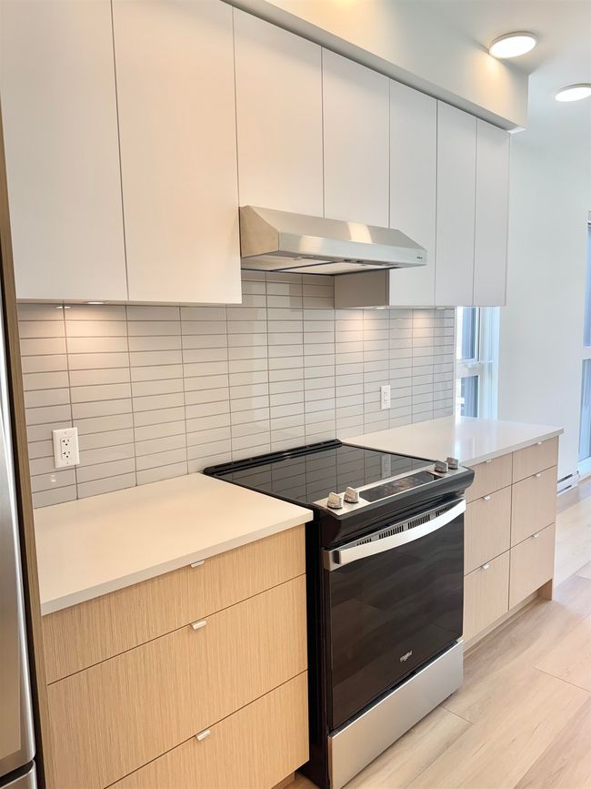 Kitchen featuring tasteful backsplash, range hood, modern cabinets, and electric stove | Image 7