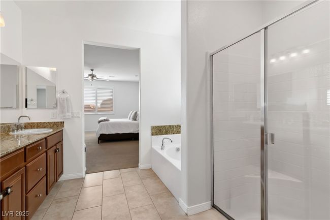 Ensuite bathroom featuring tile patterned flooring, connected bathroom, a ceiling fan, vanity, and a stall shower | Image 39