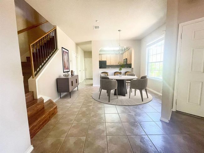 Tiled dining room with a chandelier, stairway, and baseboards | Image 5