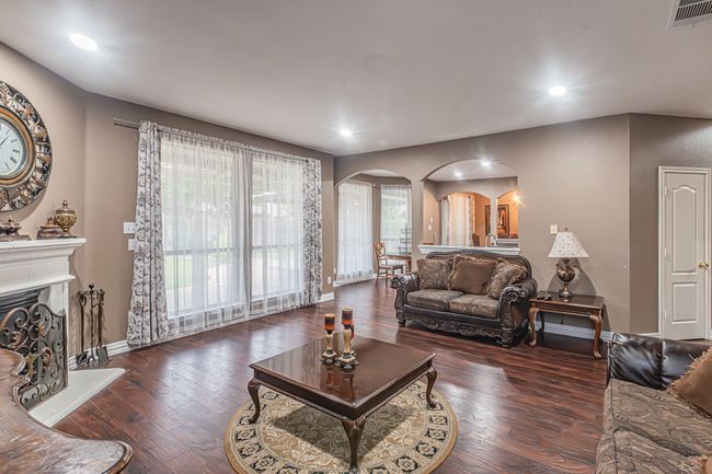 Living area featuring arched walkways, wood finished floors, recessed lighting, and a fireplace with raised hearth | Image 9