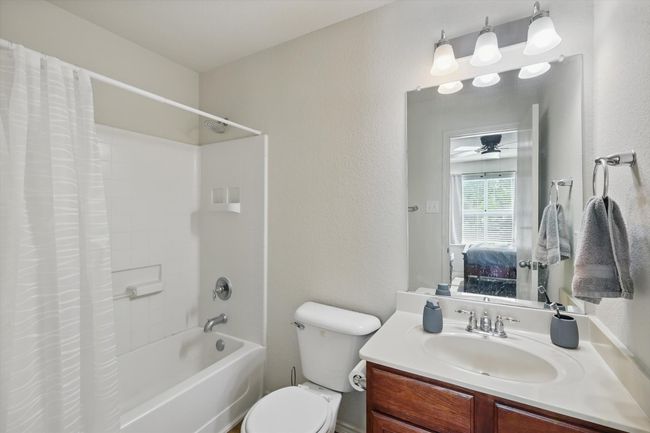Ensuite bathroom with shower / bath combo, toilet, vanity, a ceiling fan, and a textured wall | Image 17