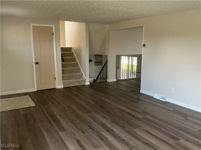 Empty room featuring a textured ceiling and dark hardwood / wood-style flooring | Image 12
