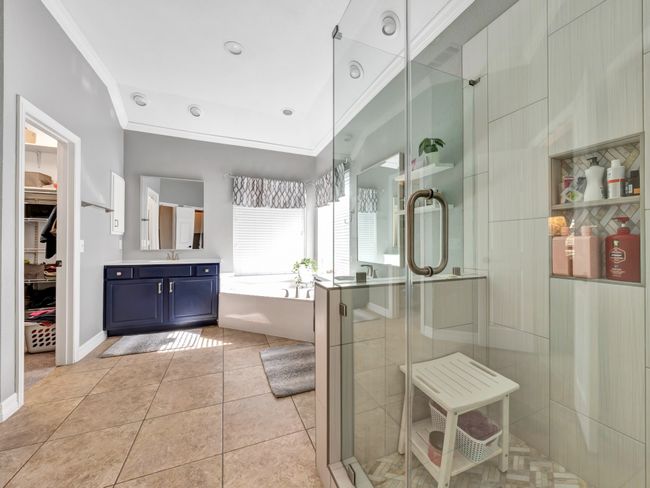 Bathroom featuring a second sink vanity, second closet, garden tub, tile flooring, a shower stall, and crown molding | Image 27