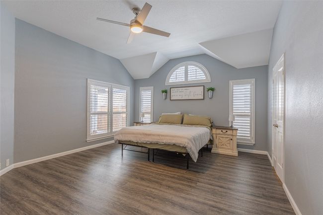 Bedroom featuring dark wood-type flooring, vaulted ceiling, baseboards, and a ceiling fan | Image 17