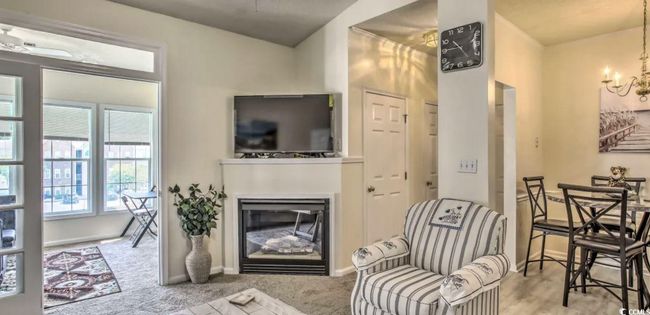 Carpeted living room with a glass covered fireplace and a chandelier | Image 7