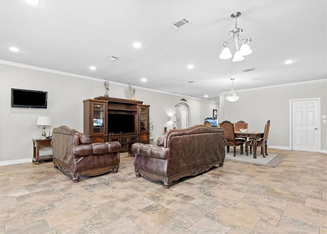 Spacious open-plan living and dining area with tiled flooring, recessed lighting, and neutral color scheme. Features include a mounted TV, classic wooden furniture, and ample natural light. | Image 44
