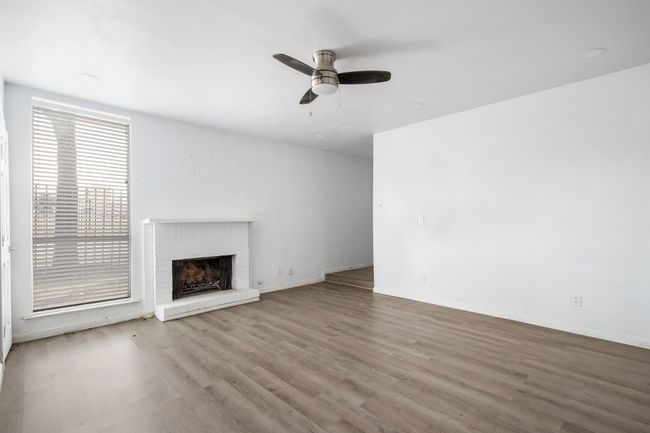 Unfurnished living room with ceiling fan, a brick fireplace, and light hardwood / wood-style floors | Image 7