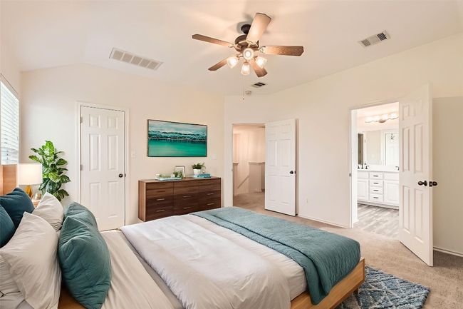 PrimaryBedroom upstairs featuring light colored carpet, ensuite bath, lofted ceiling, and ceiling fan (virtual staging) | Image 5