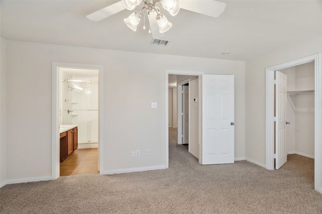 Unfurnished bedroom featuring a spacious closet, visible vents, light carpet, connected bathroom, and baseboards | Image 23