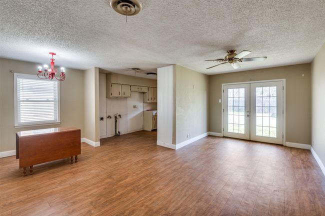 Unfurnished living room featuring french doors, ceiling fan with notable chandelier, light hardwood / wood-style flooring, and a textured ceiling | Image 9