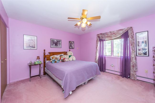 Bedroom with light carpet, baseboard heating, and a ceiling fan | Image 21