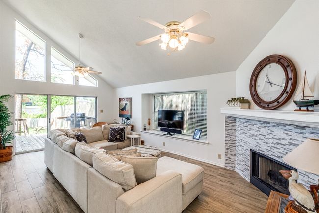 Living area with a ceiling fan, a stone fireplace, wood finished floors, and high vaulted ceiling | Image 4