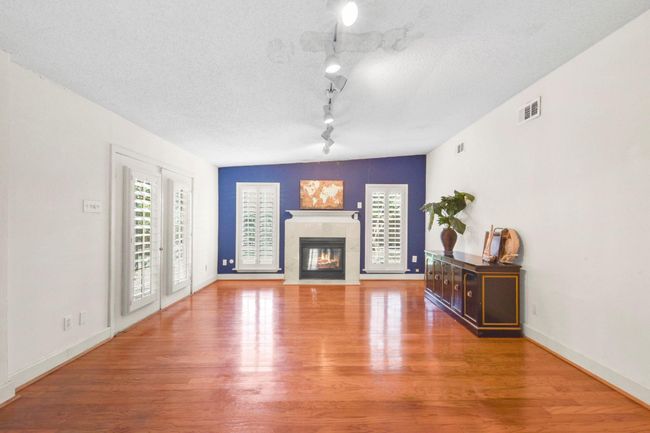 Cozy den featuring a fireplace, elegant plantation shutters, and direct access to the back porch. | Image 6