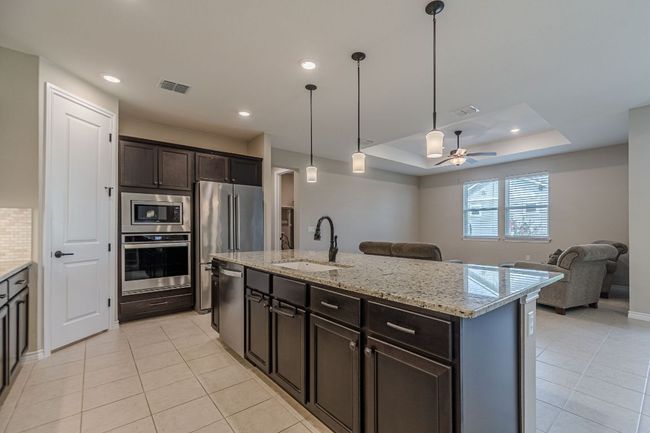 Kitchen with a raised ceiling, appliances with stainless steel finishes, open floor plan, a ceiling fan, and light tile patterned floors | Image 11