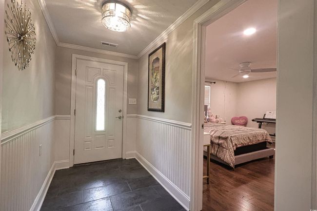 Foyer entrance with wainscoting, healthy amount of natural light, ceiling fan, and crown molding | Image 23