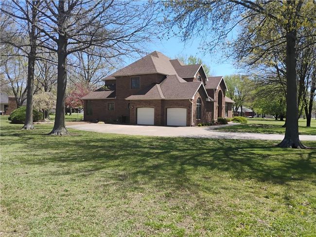 View of home's exterior featuring a lawn, brick siding, roof with shingles, and driveway | Image 6