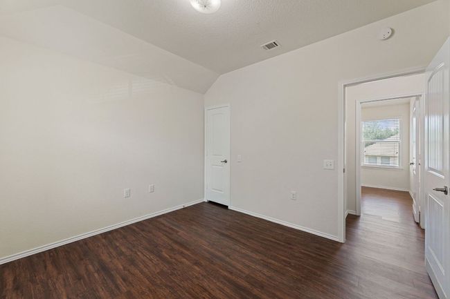 Empty room with dark wood-style floors, lofted ceiling, and a smoke detector | Image 19