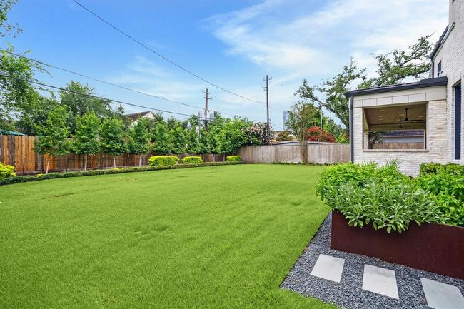From the downstairs bedroom, step out into the spacious backyard with lush green lawn, privacy fence, and landscaped garden beds. Ideal for outdoor activities and entertaining with plenty of space for a pool. | Image 30