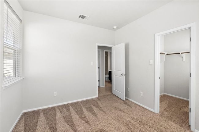 Unfurnished bedroom featuring a closet, baseboards, carpet floors, a walk in closet, and visible vents | Image 21