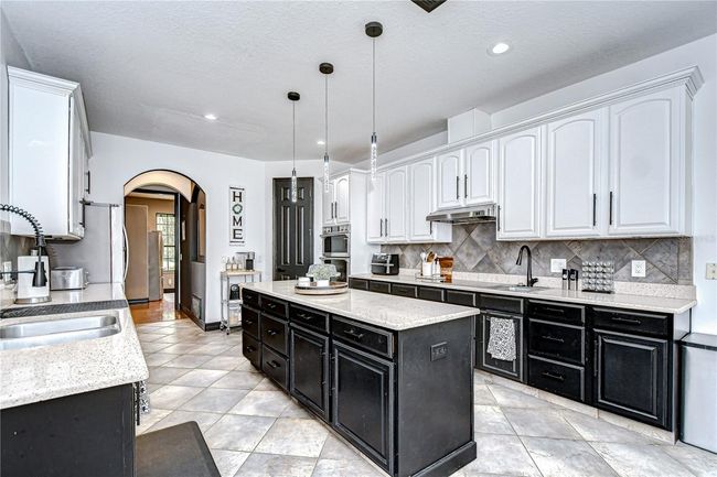 Enjoy granite countertops, a tile backsplash, a large center island, wall oven, cooktop, & walk-in pantry! | Image 10