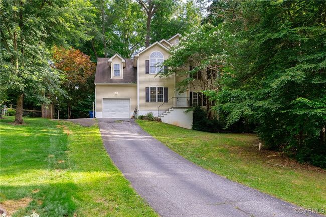 View of front of property featuring driveway, a front yard, and view of wooded area | Image 27